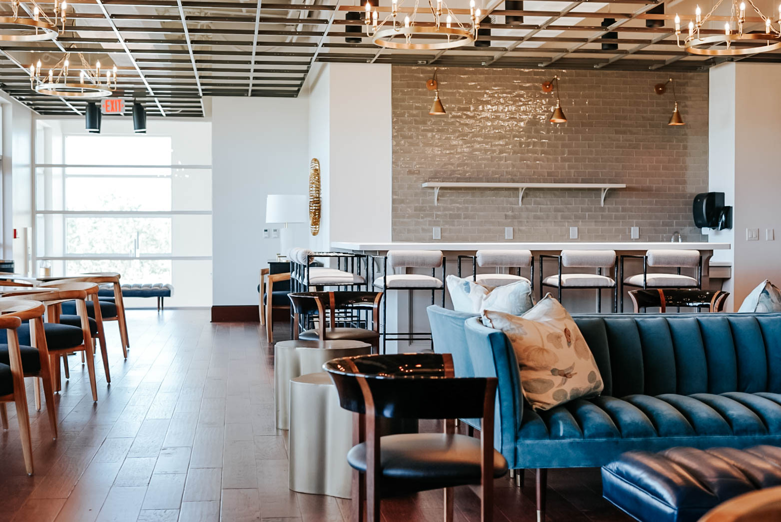 Modern lounge with blue velvet sofa, bar seating, and wood floors