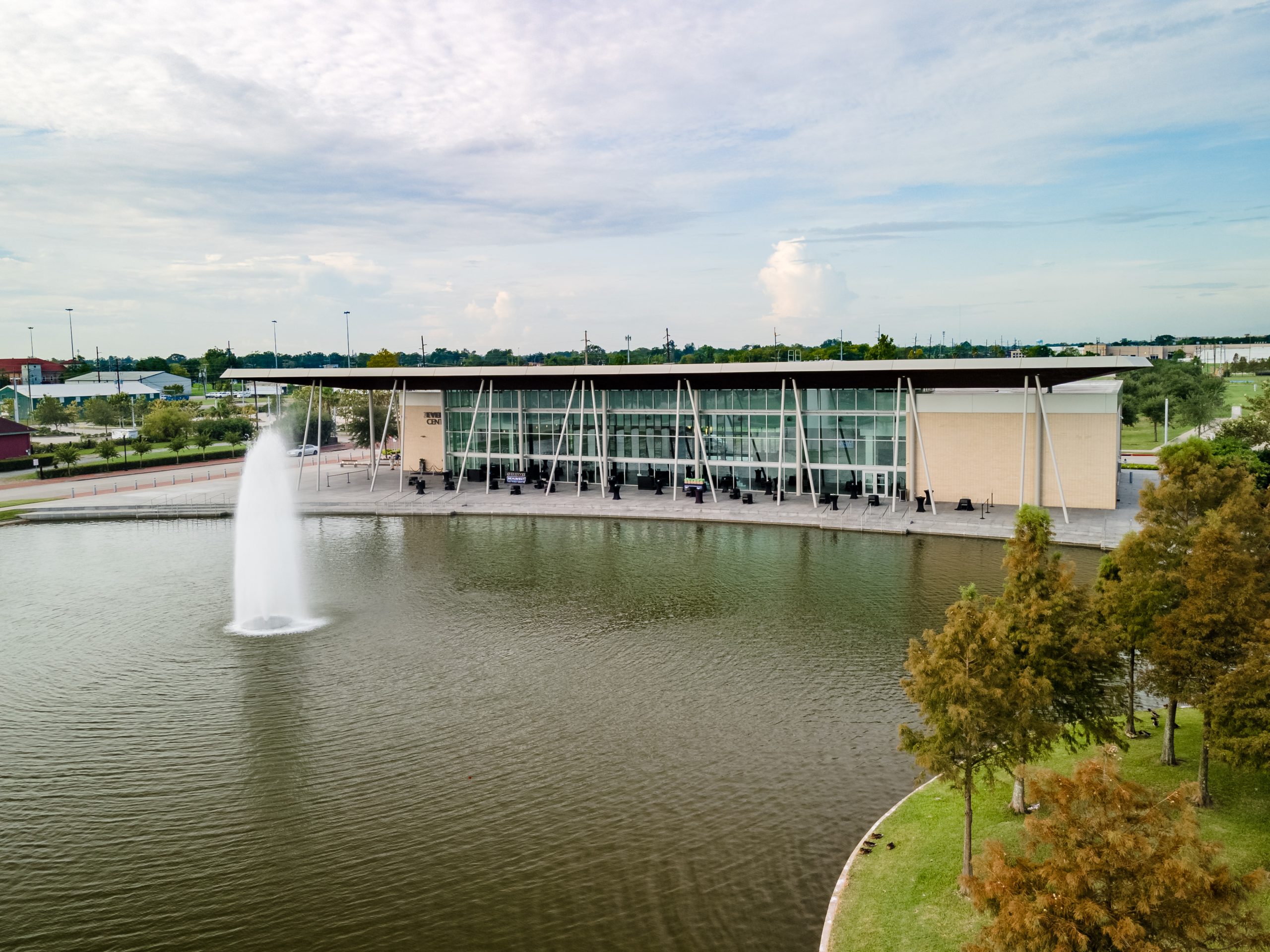Modern building with glass facade and fountain in foreground pond.