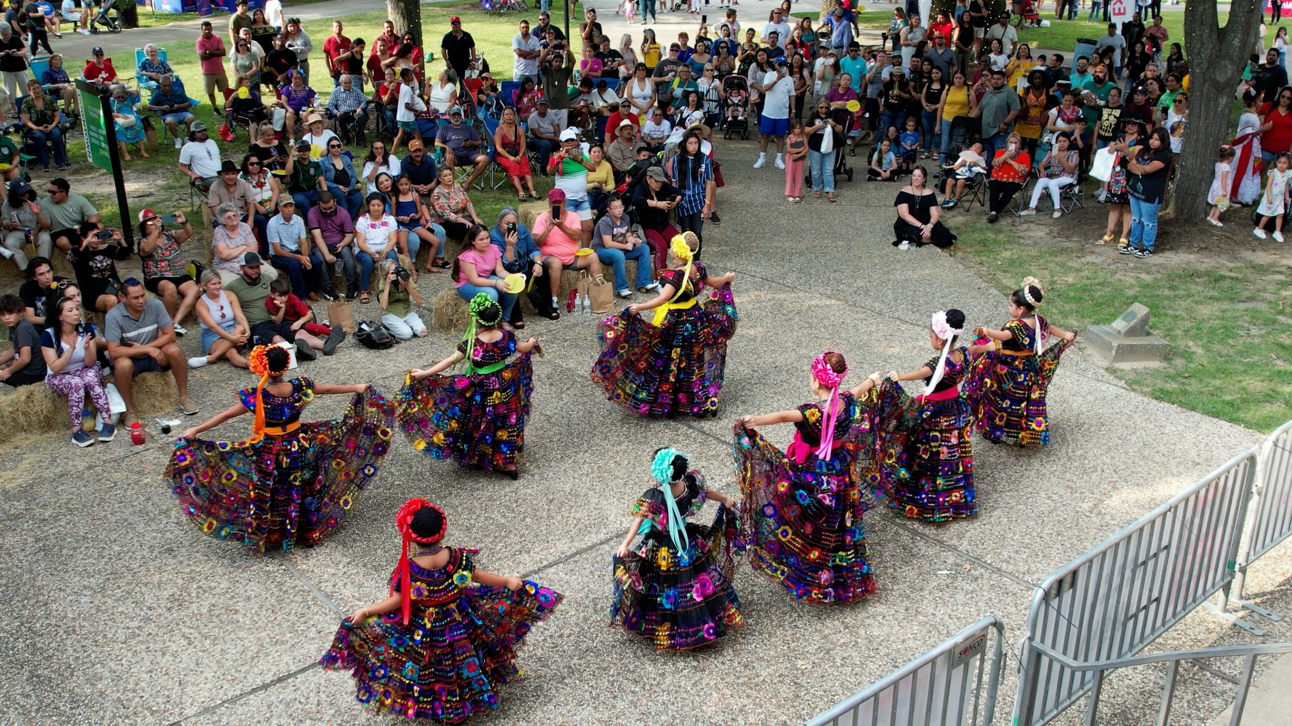 Dancers in colorful traditional dresses perform at an outdoor festival.