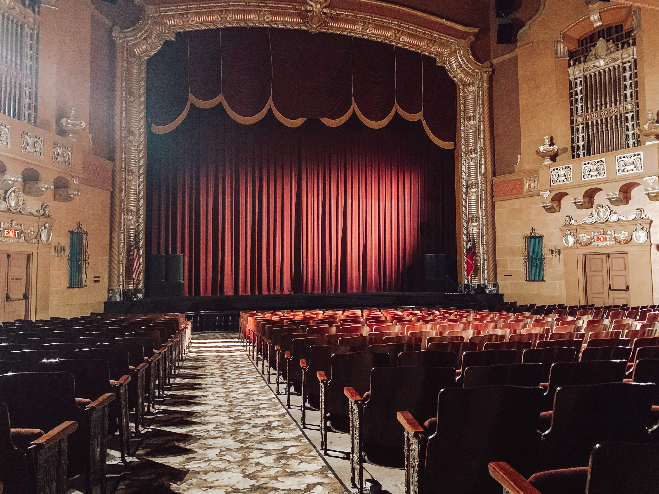 Empty vintage theater with red velvet curtains and rows of seats.